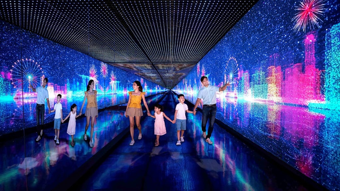 Families walking through the Time Capsule at Singapore Flyer with digital cityscape and fireworks.