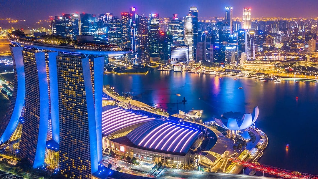 Singapore skyline at night viewed from the Singapore Flyer, featuring Marina Bay Sands and city lights.