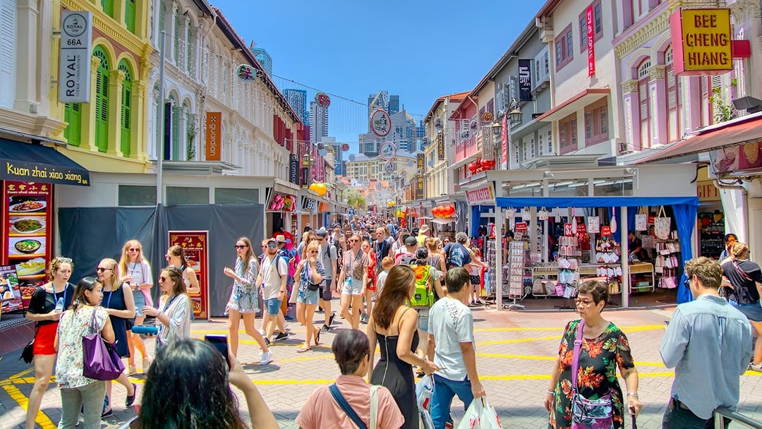 Crowded street in Chinatown, Singapore with colorful shophouses and tourists exploring.