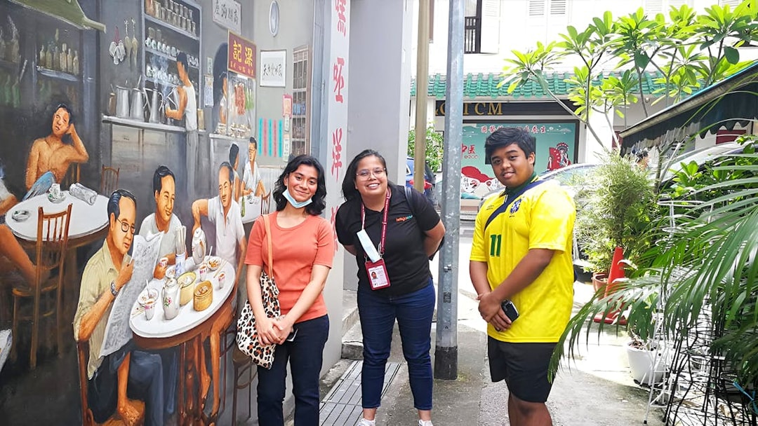 Tourists posing by a mural in Chinatown during the Guided City Highlights Tour.