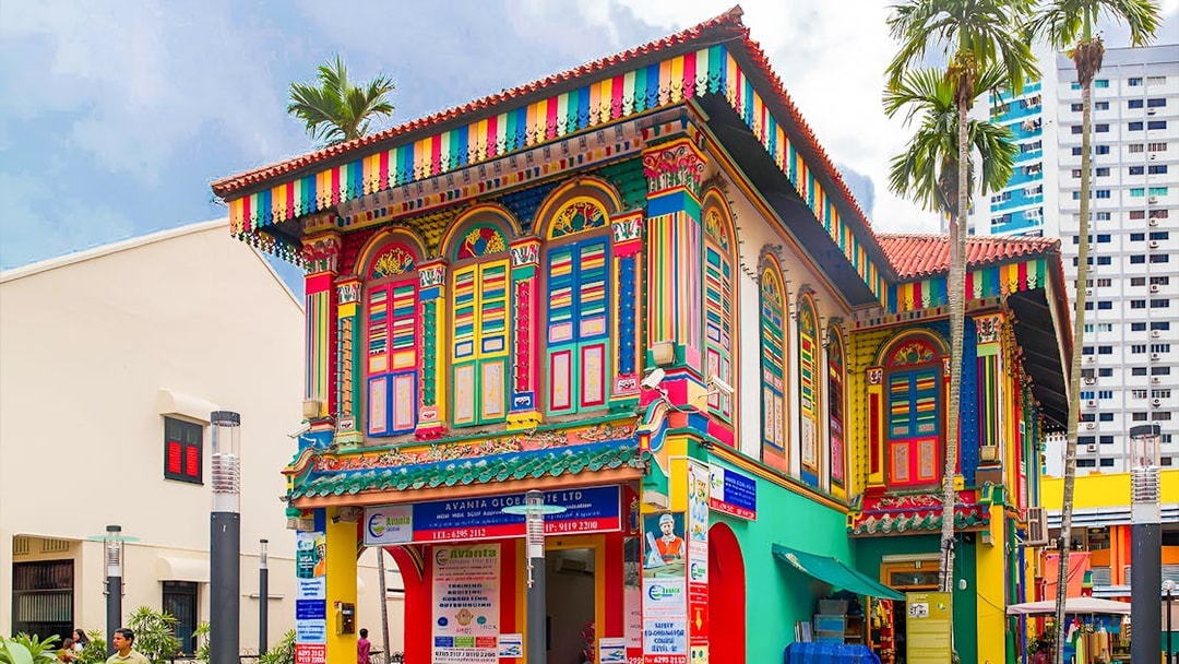 Colorful heritage building in Little India, Singapore, featuring vibrant architecture and palm trees.