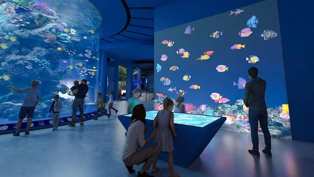 Colourful fishes in large tank at Singapore Oceanarium with visitors observing.