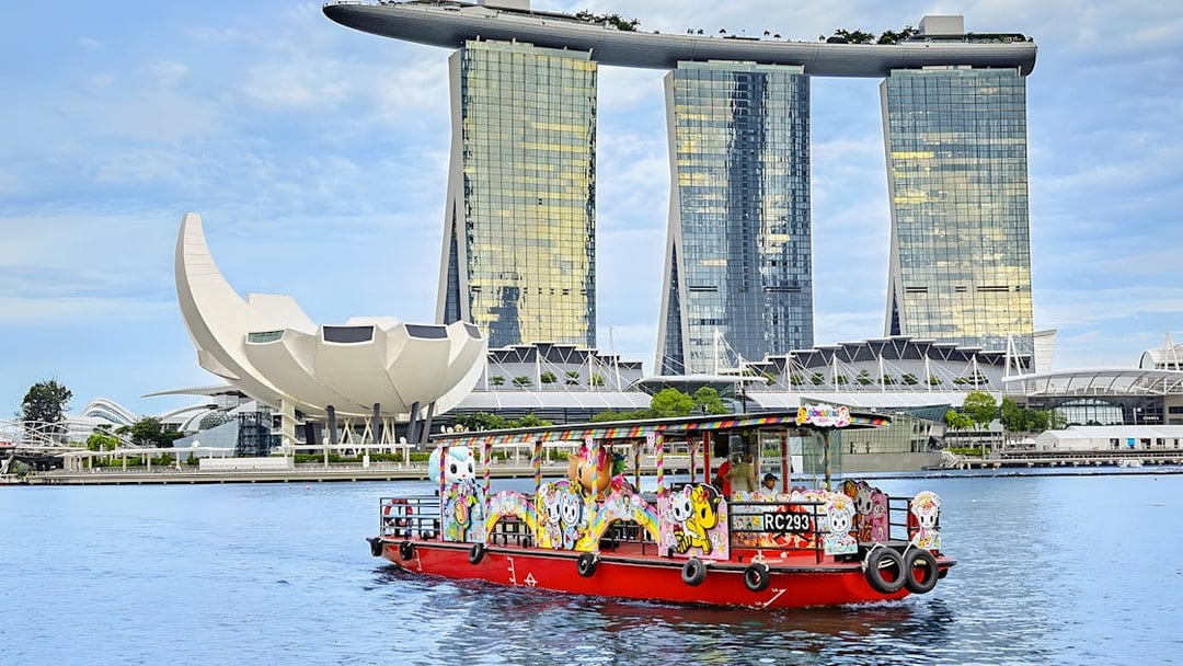 Singapore River Cruise boat with colorful designs in front of Marina Bay Sands.