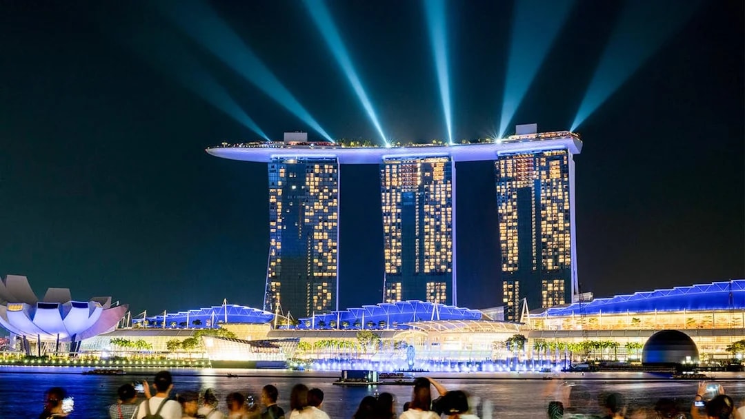 Marina Bay Sands SkyPark illuminated at night in Singapore with crowds viewing.