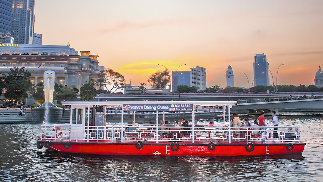 Singapore River Cruise boat by WaterB passing Merlion Park at sunset.