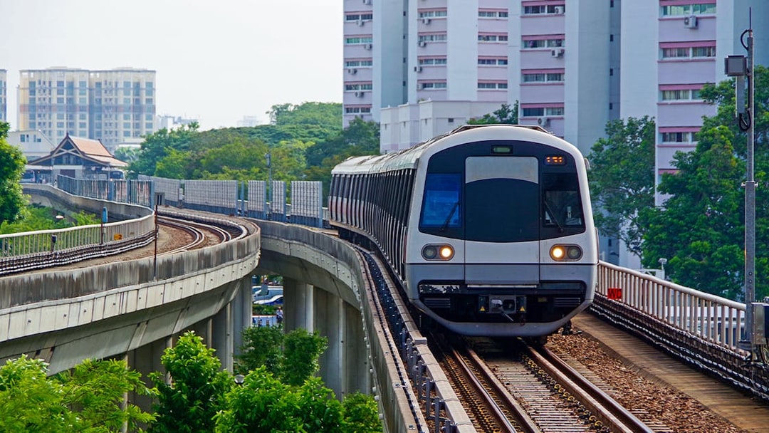 Singapore Metro train on elevated tracks with city buildings in the background.