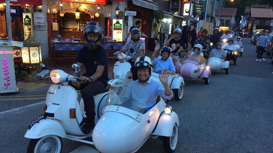Group enjoying a vintage Vespa sidecar tour at night in Singapore street.