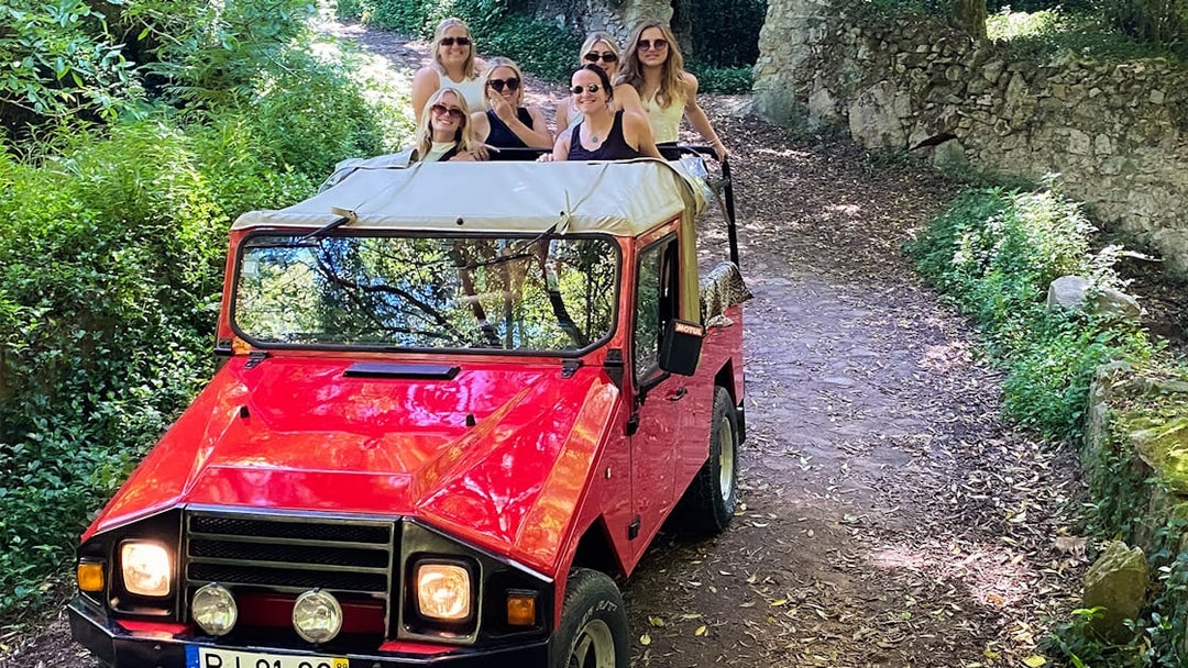 Red jeep with tourists on a forest trail during a guided safari tour in Sintra, Portugal.