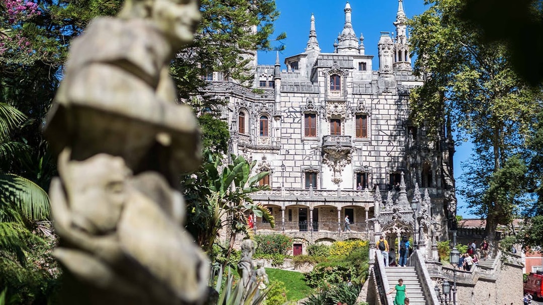 Quinta da Regaleira in Sintra with tourists exploring gardens and architecture.