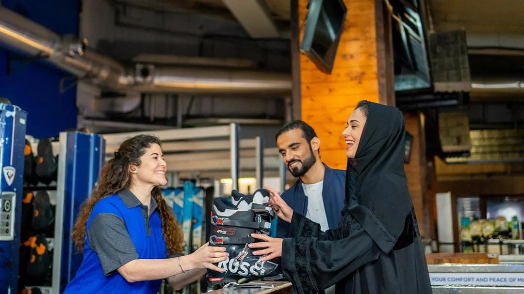 Ski Dubai visitors receiving ski boots from staff at Snow Park entrance.