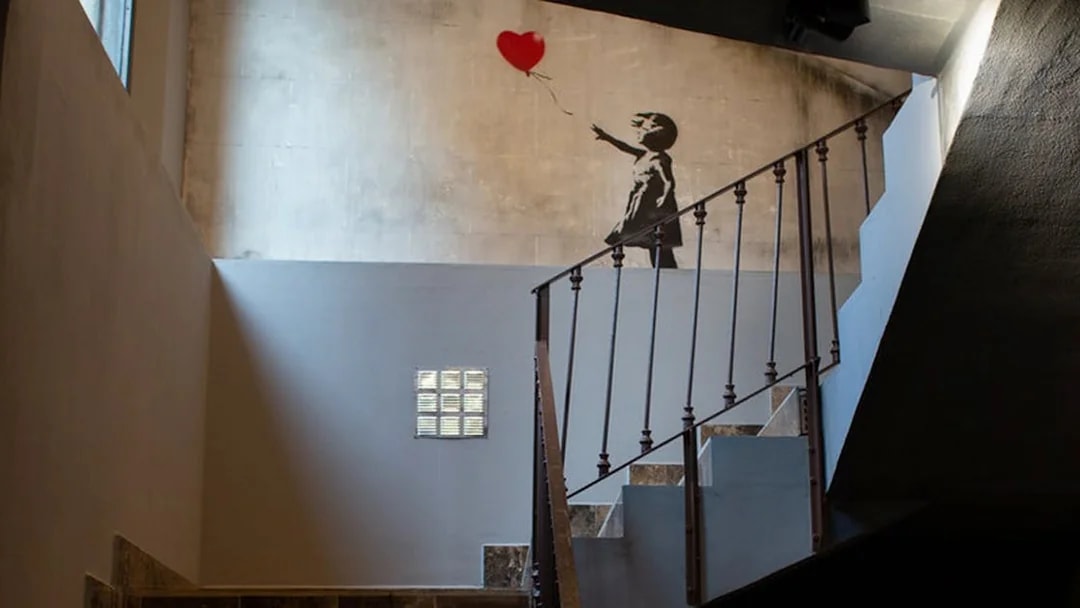 Banksy mural of girl with balloon at Banksy Museum Barcelona staircase.