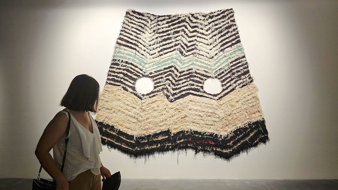 Visitor viewing textile art at Centre Pompidou Malaga exhibition interior.