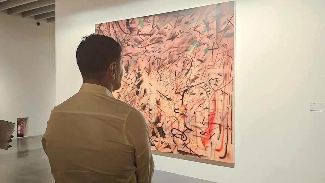 Man viewing abstract painting at Centre Pompidou Malaga exhibition.
