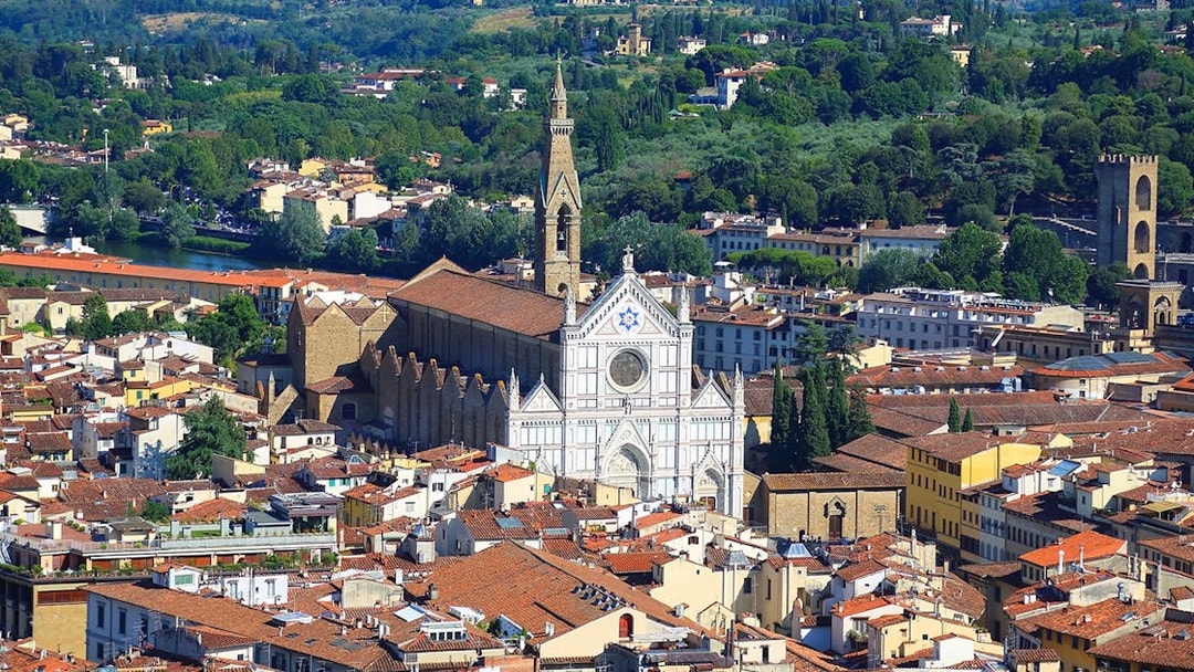 Aerial view of Santa Croce Basilica in Florence, Italy, surrounded by cityscape and greenery.