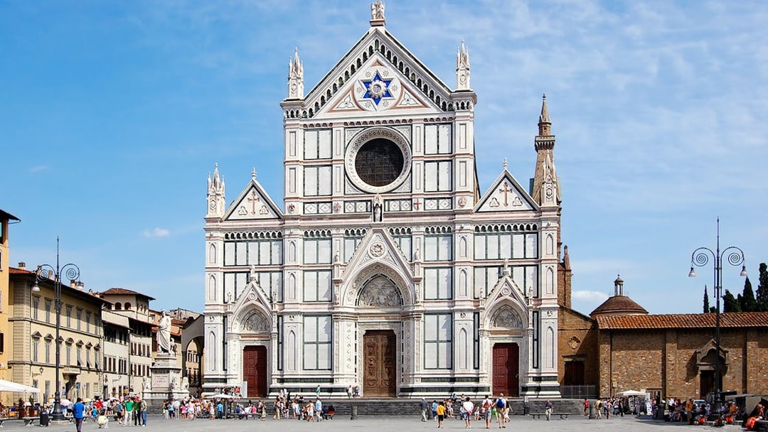 Santa Croce Basilica facade in Florence, Italy, with tourists in the foreground.