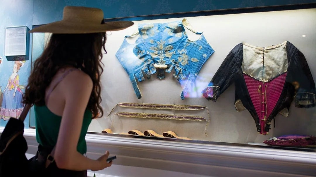 Visitor viewing historical silk garments at Silk Museum Valencia exhibit.