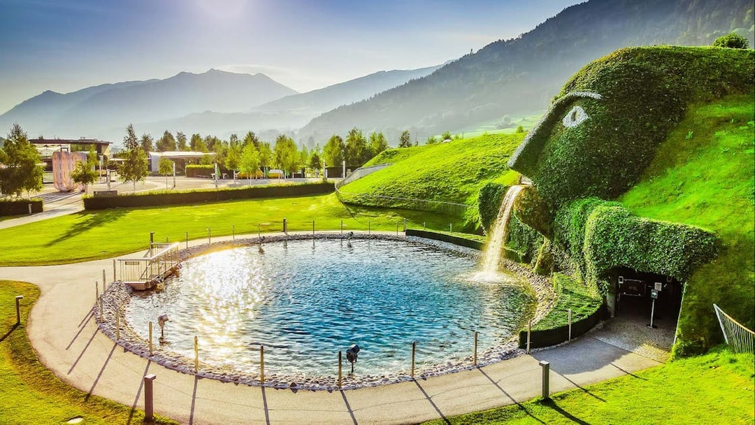 Swarovski Crystal Worlds entrance with giant grass-covered head and waterfall in Innsbruck, Austria.