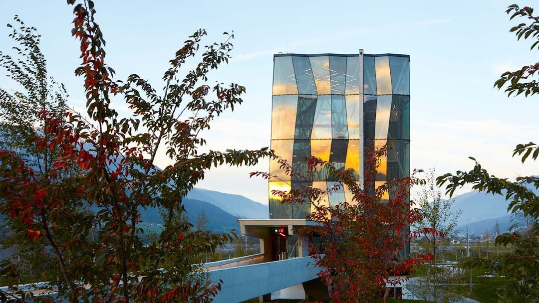 Swarovski Crystal Worlds entrance with modern glass architecture and surrounding trees.