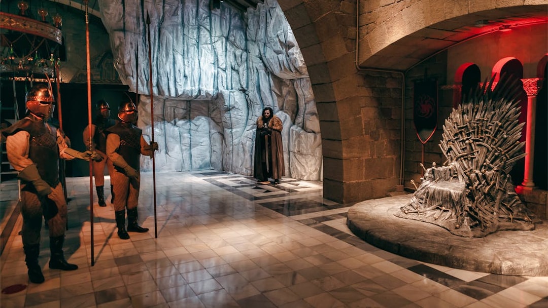 Wax figures in medieval attire near a throne at Wax Museum Barcelona.