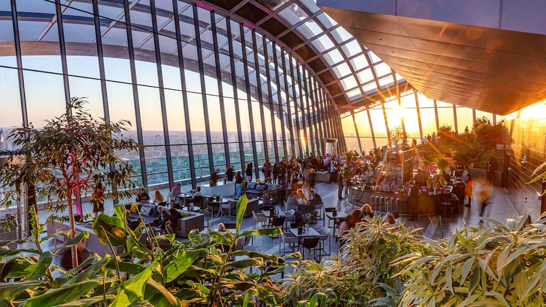 Sky Garden London evening view with people dining and cityscape backdrop.