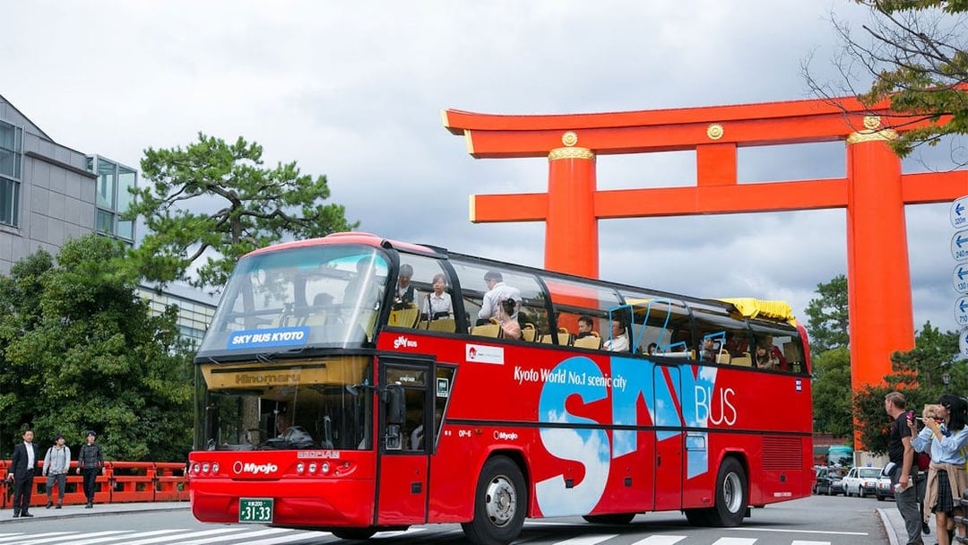 Sky Hop Bus passing a large red torii gate in Kyoto.