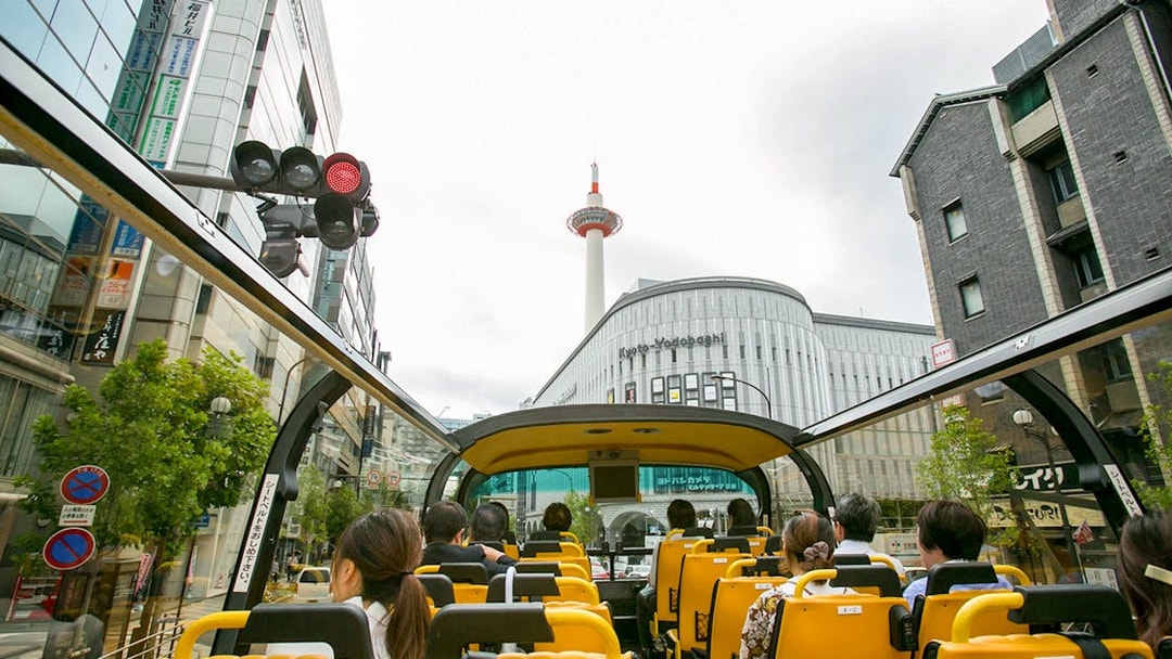 Open-top bus tour in Kyoto passing Kyoto Tower and city buildings.