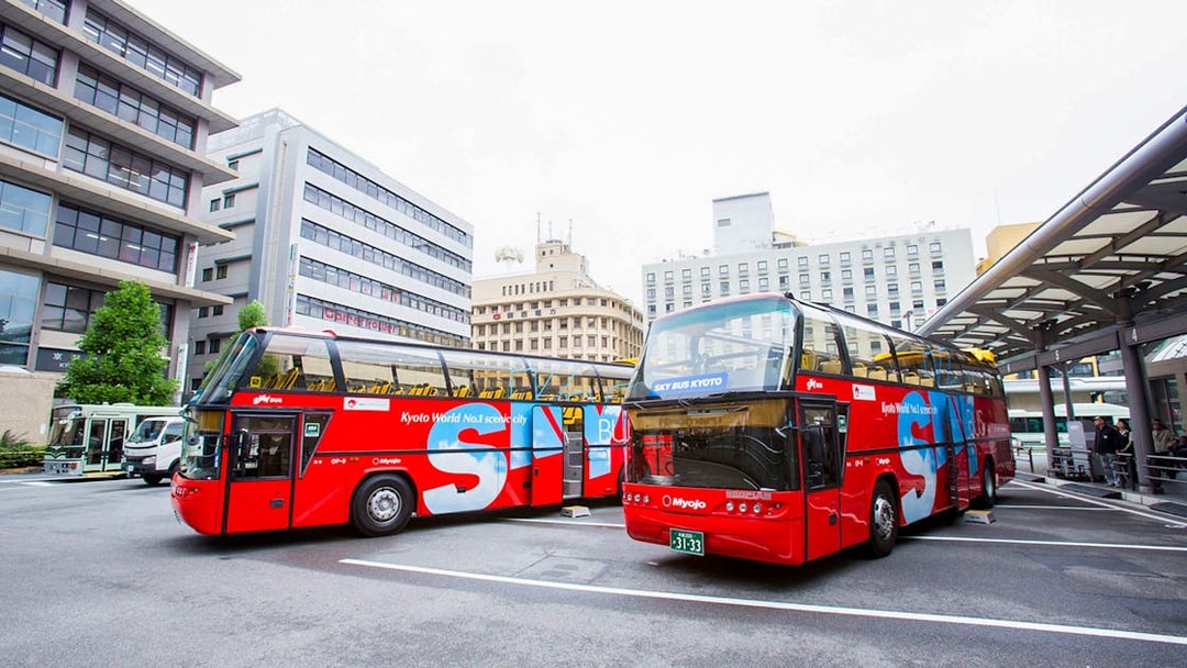 Kyoto sightseeing hop-on hop-off buses parked at a city bus terminal.