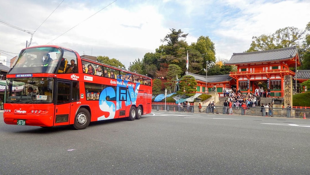 Kyoto sightseeing bus passing by Yasaka Shrine with tourists on board.