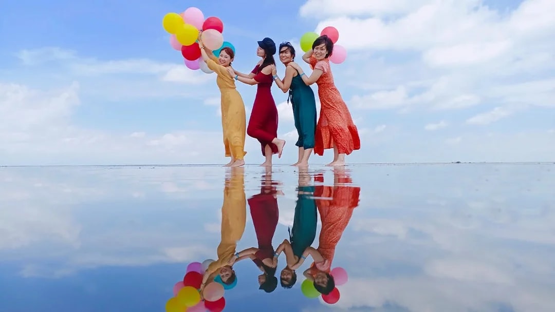 Group enjoying Sky Mirror Experience in Kuala Selangor with colorful balloons reflected on water.