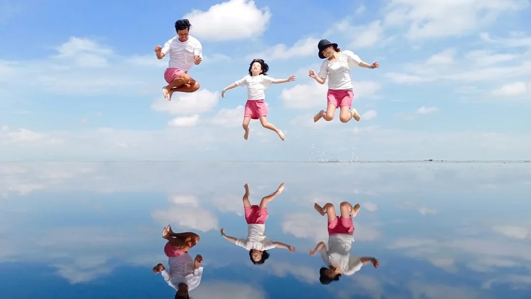 People jumping with reflections on water at Sky Mirror, Kuala Selangor.