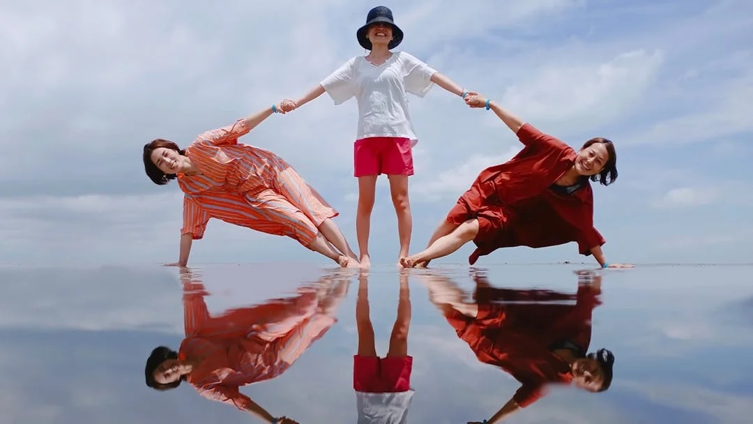 Three people posing on reflective water at Sky Mirror, Kuala Selangor.