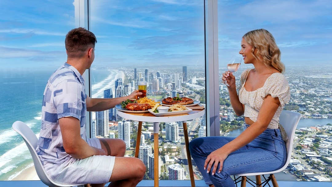 Couple dining with ocean and city views at SkyPoint Observation Deck, Gold Coast.