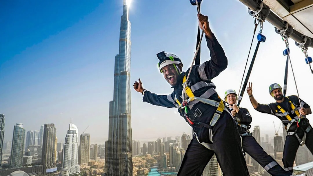 People enjoying a zipline experience with a view of the Burj Khalifa in Dubai.