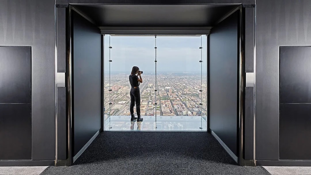 Person photographing cityscape from Skydeck Chicago at Willis Tower.
