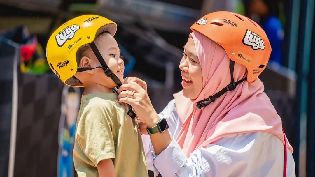 Woman adjusting child's helmet at The Skyline Luge, Kuala Lumpur.
