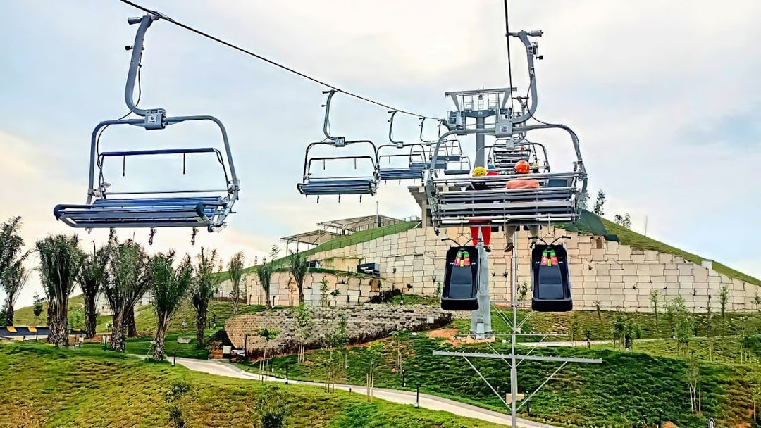 Chairlift ascending to The Skyline Luge in Kuala Lumpur with lush greenery below.