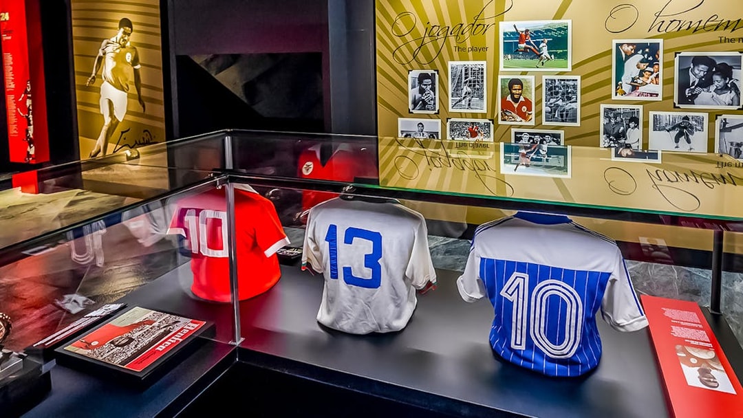 Benfica Stadium museum display with historic football jerseys and player photos.