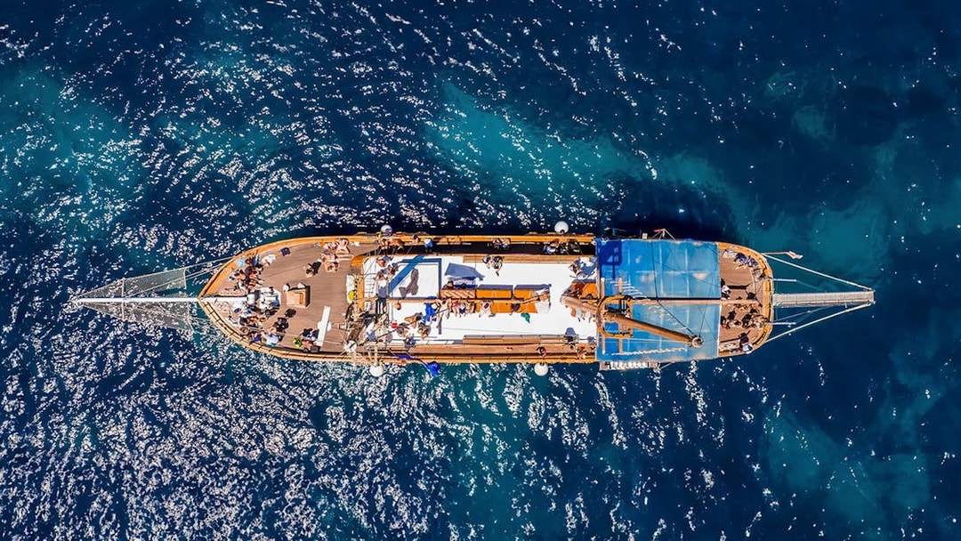 Turkish gulet sailing from Sliema to Gozo and Comino, passengers enjoying lunch on deck.