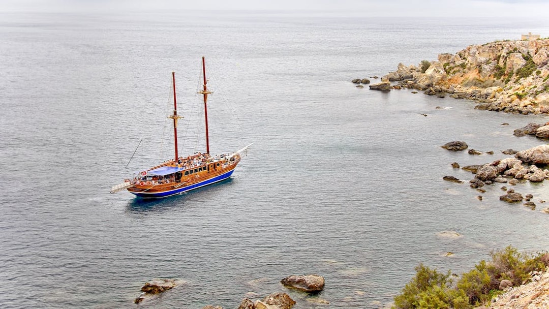 Turkish gulet sailing near rocky coast from Sliema to Gozo and Comino.