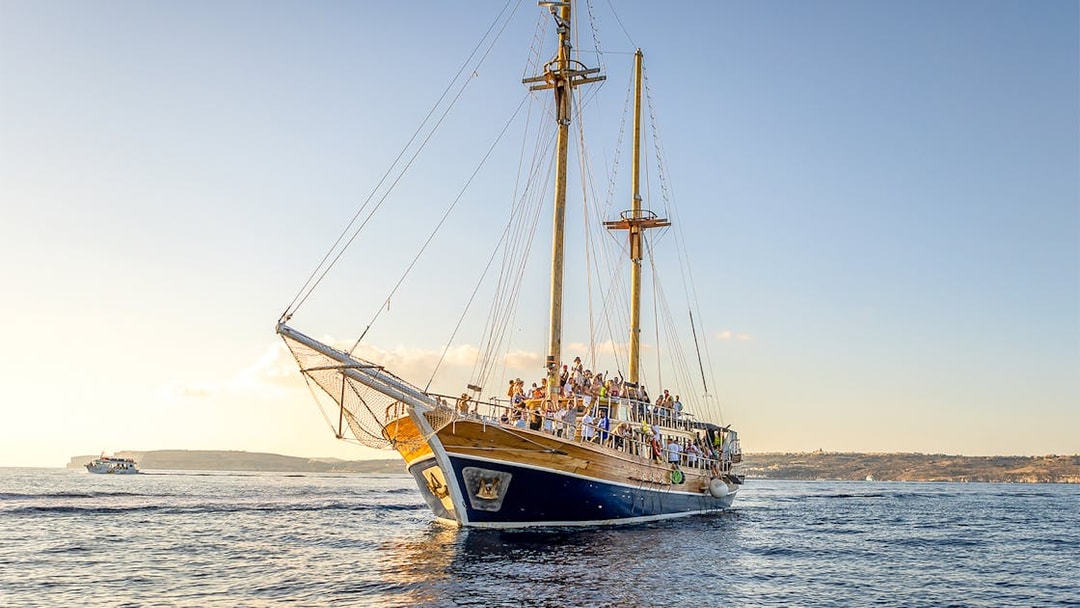 Cruise ship sailing near Gozo and Comino Islands at sunset.