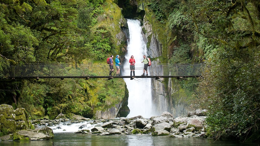 Group on bridge with waterfall view during Giant Gate Falls walking tour.
