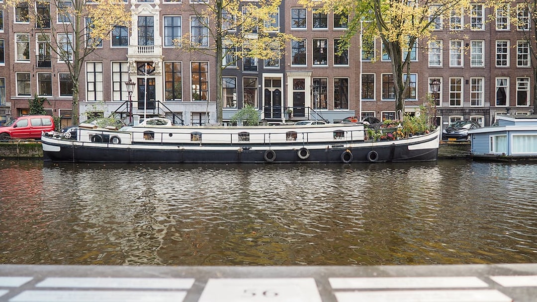 Canal boat on Amsterdam canal with historic buildings in the background.