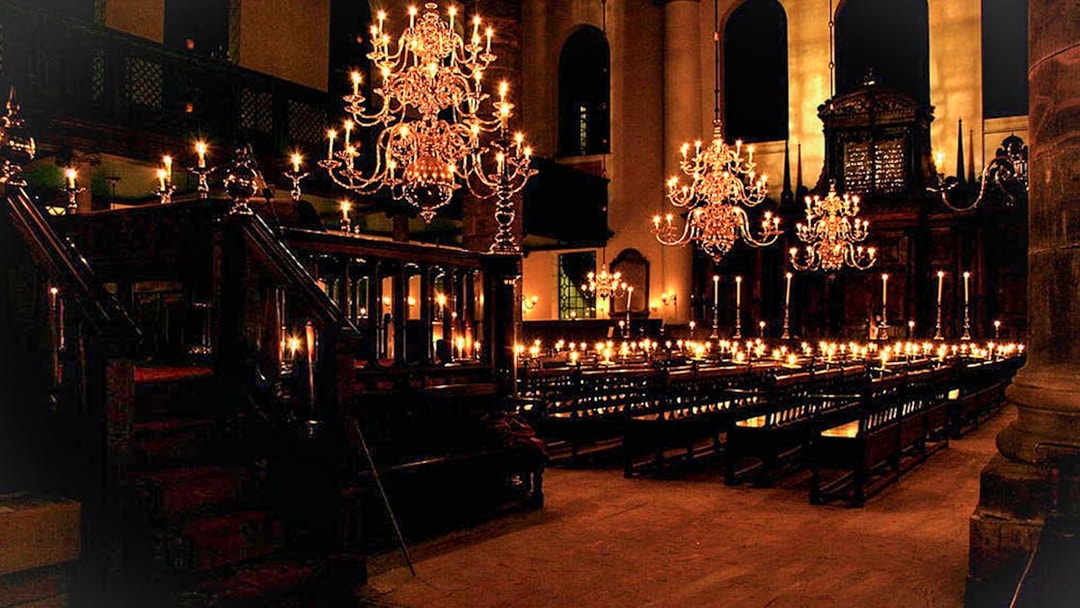 Interior of a historic synagogue with chandeliers and wooden pews, part of a Jewish history tour.