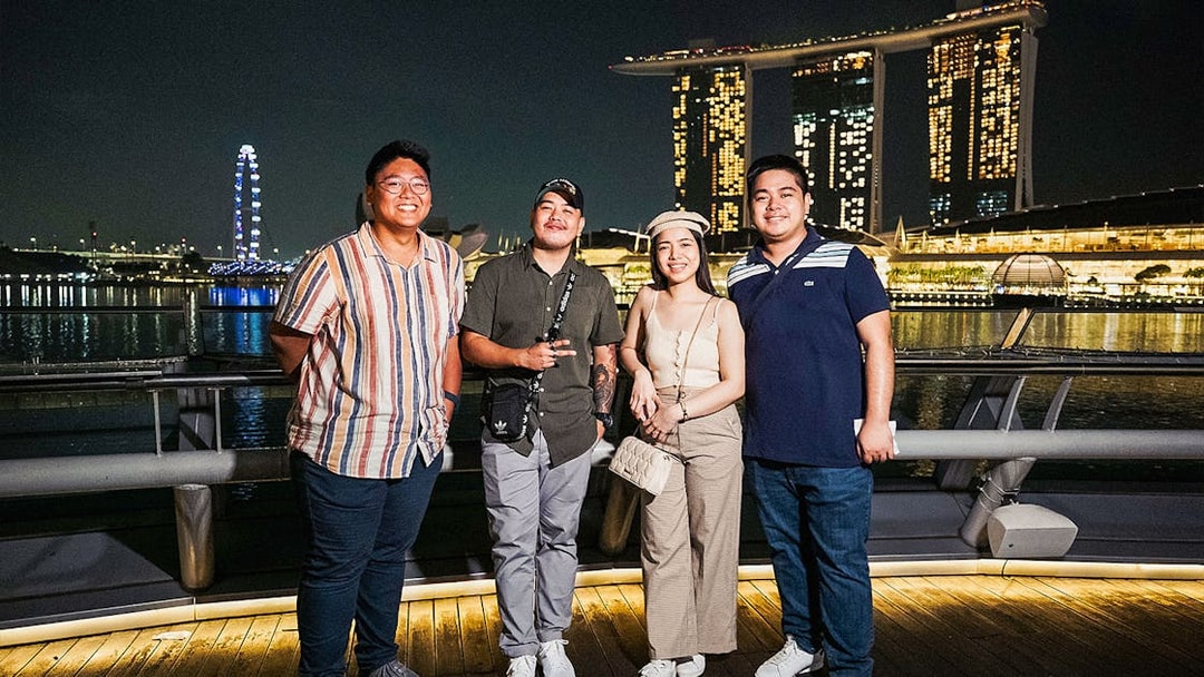 Group enjoying Singapore night tour with Marina Bay Sands and Singapore Flyer in the background.