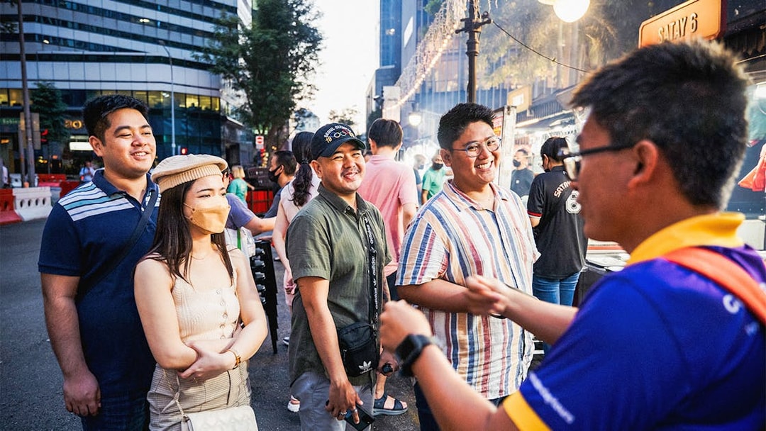 Tour group enjoying Singapore street food night tour with guide.