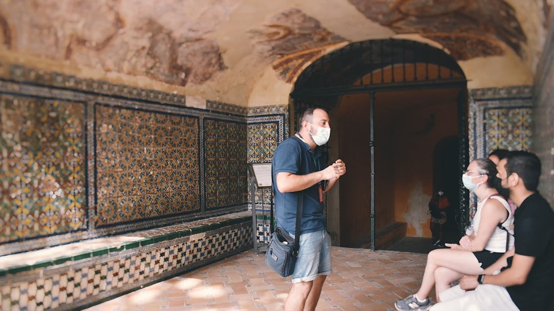 Guide explaining Alcázar's tiled walls to visitors on a tour.