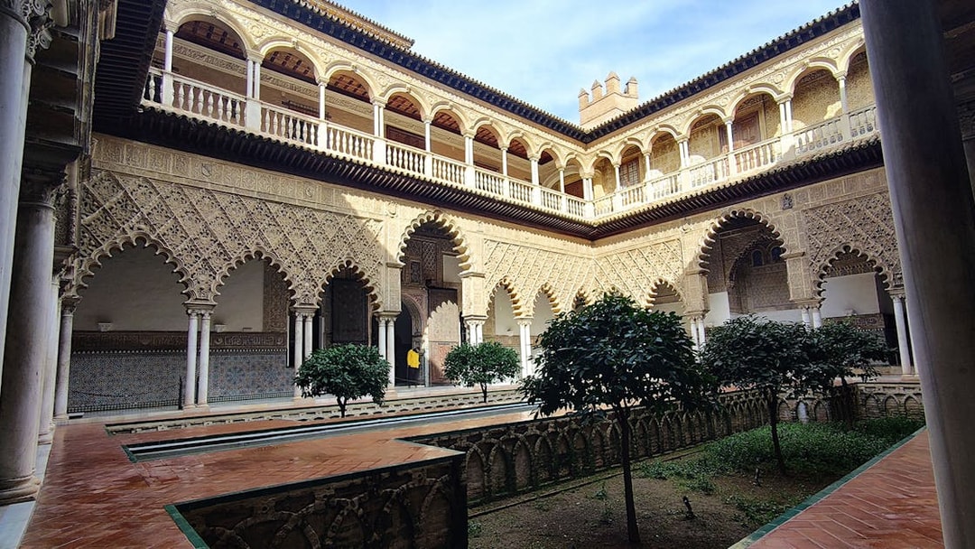 Alcázar courtyard with intricate arches and lush greenery, Seville guided tour.