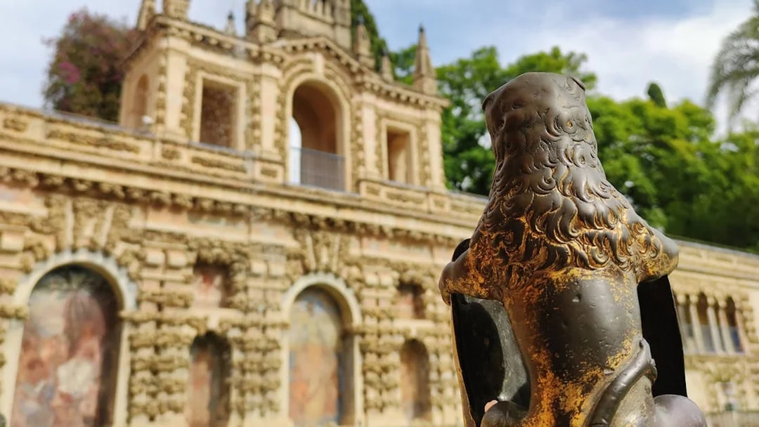 Lion statue in front of the Alcázar's ornate facade, Seville, Spain.
