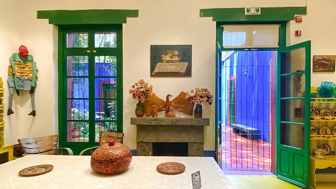 Frida Kahlo Museum interior with vibrant decor and open doors to colorful courtyard.