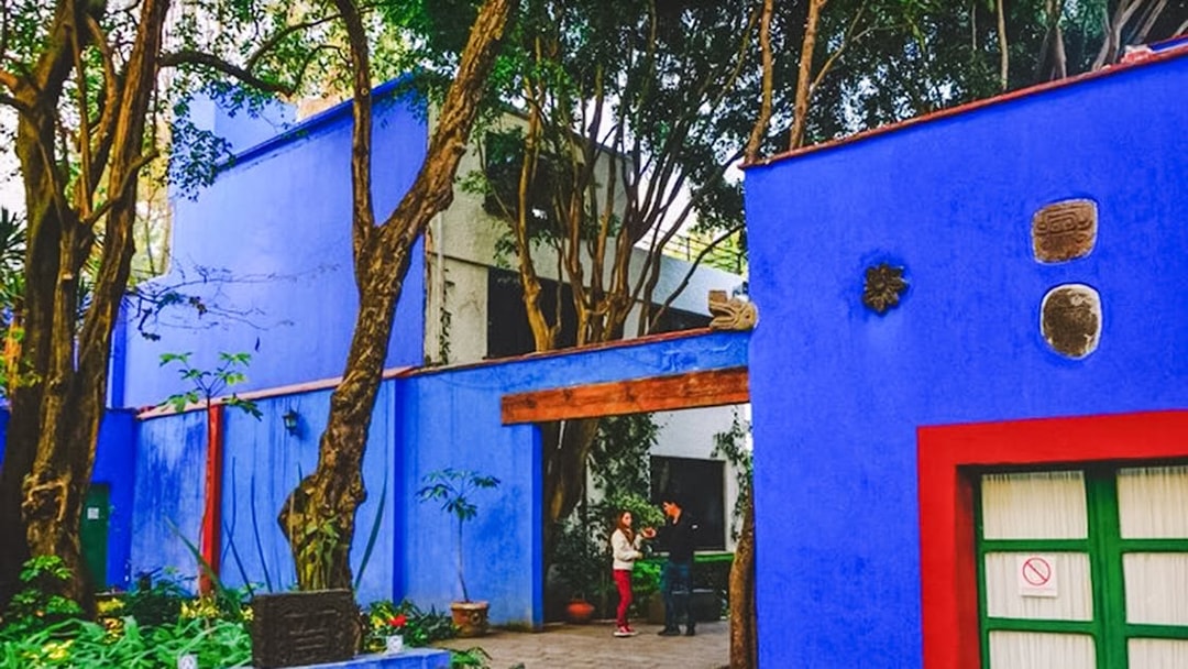 Frida Kahlo Museum courtyard with vibrant blue walls and lush greenery, Mexico City.